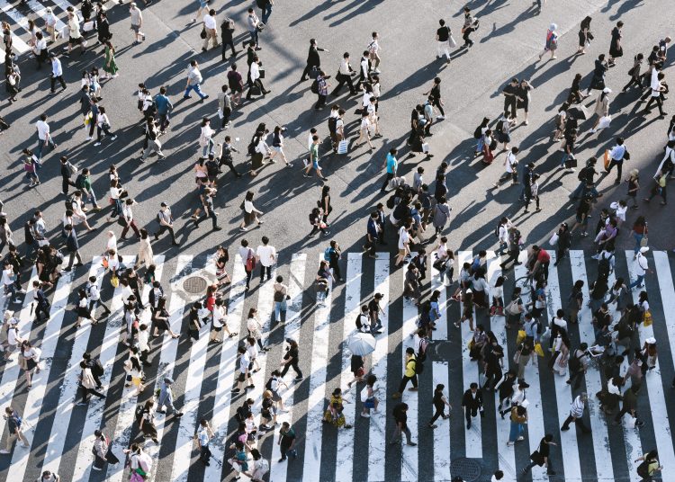 a large group of people seen from overhead crossing a street in multiple directions